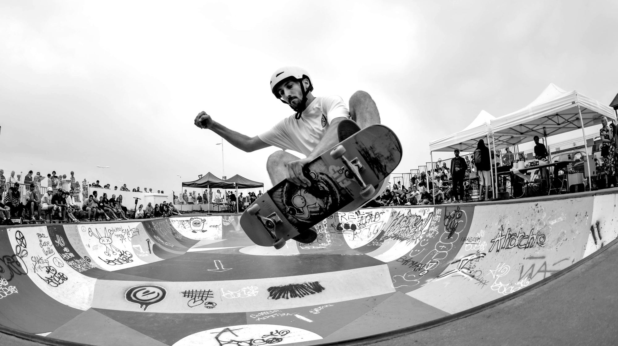 Un skater en l'air au-dessus d'un bowl, le public autour.